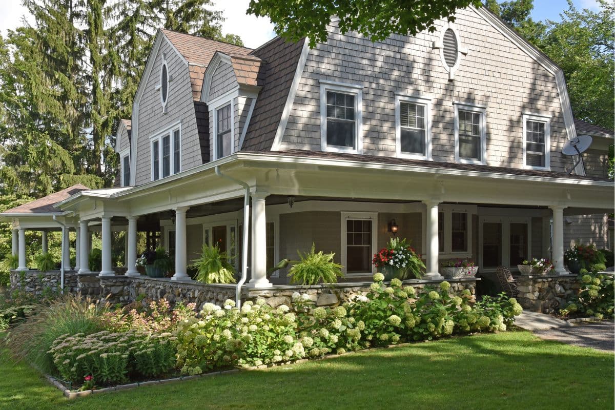 A charming two-story house with a wraparound porch and landscaped garden.